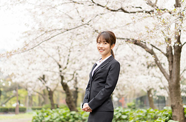 桜の木の下に立つスーツを着た女性